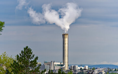 Concrete chimney of waste incineration plant with white smoke on a cloudy summer morning at City of Zürich, Switzerland.